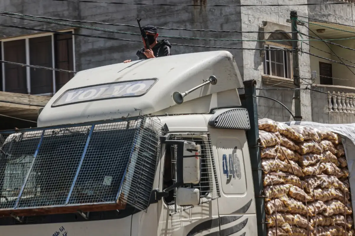 Un miembro enmascarado de los llamados "Comités de Protección del Pueblo" vigila un camión de ayuda humanitaria en Rafah, en el sur de la Franja de Gaza, el 3 de abril de 2024, mientras continúa el conflicto entre Israel y el grupo palestino de Hamas