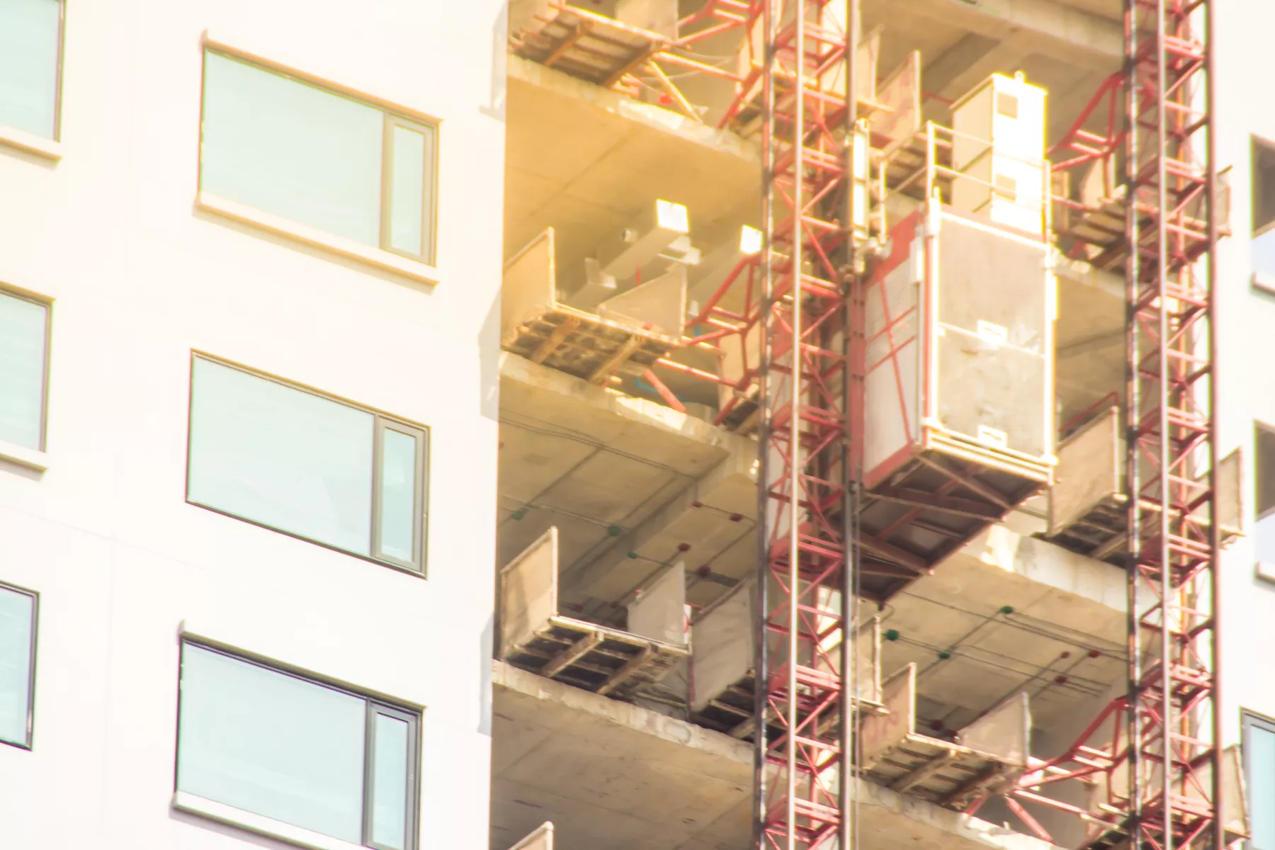 Elevator in high building construction site for transport construction workers up unfinished buildings. Passenger and material hoist transport platform for vertical transportation of man and material.