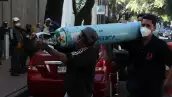 Tres hombres cargan un tanque de oxígeno grande para rellenarlo en la colonia Escandón.
