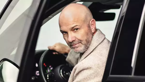 Foto del comentarista de futbol Luis García saliendo de un auto con la mano al volante.