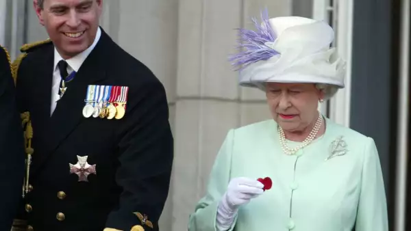 La reina Isabel II sostiene una amapola caída de una bomba Lancaster mientras está de pie junto al príncipe Andrés en el balcón del Palacio de Buckingham durante las celebraciones que marcan el final de la Segunda Guerra Mundial en Londres el 10 de julio de 2005.
