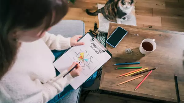 Woman drawing work-life balance wheel sitting on the sofa at home. 
