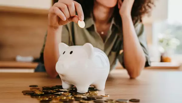 Worried young woman saving last coins in piggy bank