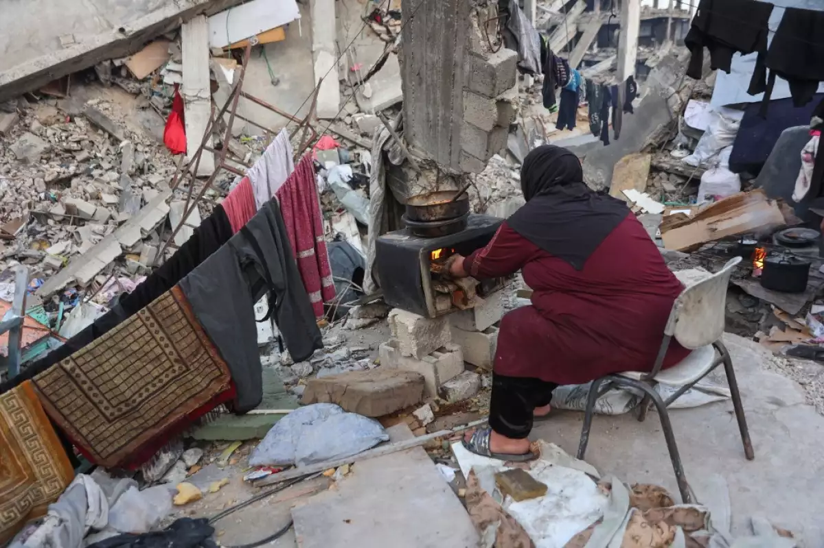 Una mujer palestina cocina en una estufa improvisada en los escombros de un edificio donde su familia se refugió en Beit Lahia, en el norte de la Franja de Gaza, antes de la comida de ruptura rápida iftar durante el mes sagrado musulmán del Ramadán el 9 de marzo de 2025. El ministro de energía de Israel dijo el 9 de marzo que había dado instrucciones para dejar de suministrar electricidad a Gaza, una semana después de que Israel bloqueara toda la ayuda en el territorio palestino devastado por la guerra.
