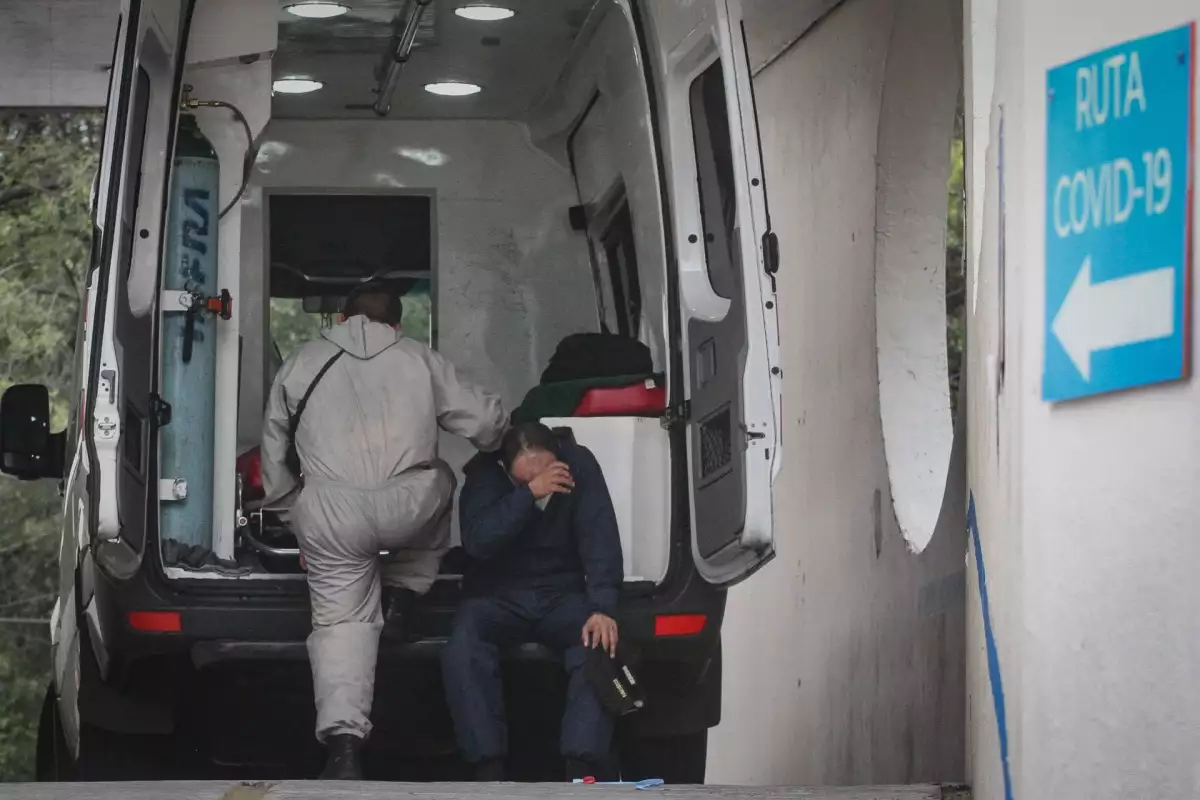 Un paramédico descansa sentado en la defensa de una ambulancia