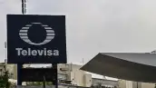 Un cartel con el logo de Televisa en medio de dos edificios. 