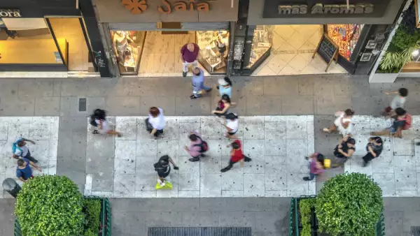 Personas caminando frente a tiendas comerciales.