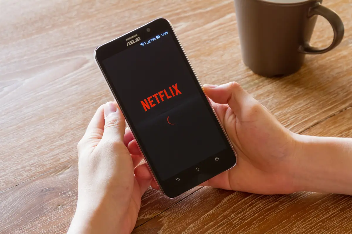 La suscripción de Netflix con anuncios está más cerca. (Unas manos sosteniendo un smartphone en el que se ve el logo de Netflix). 