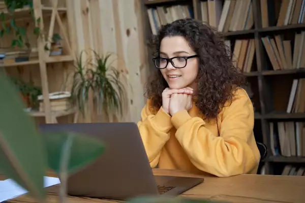 Mujer estudiante viendo su laptop en una habitación.
