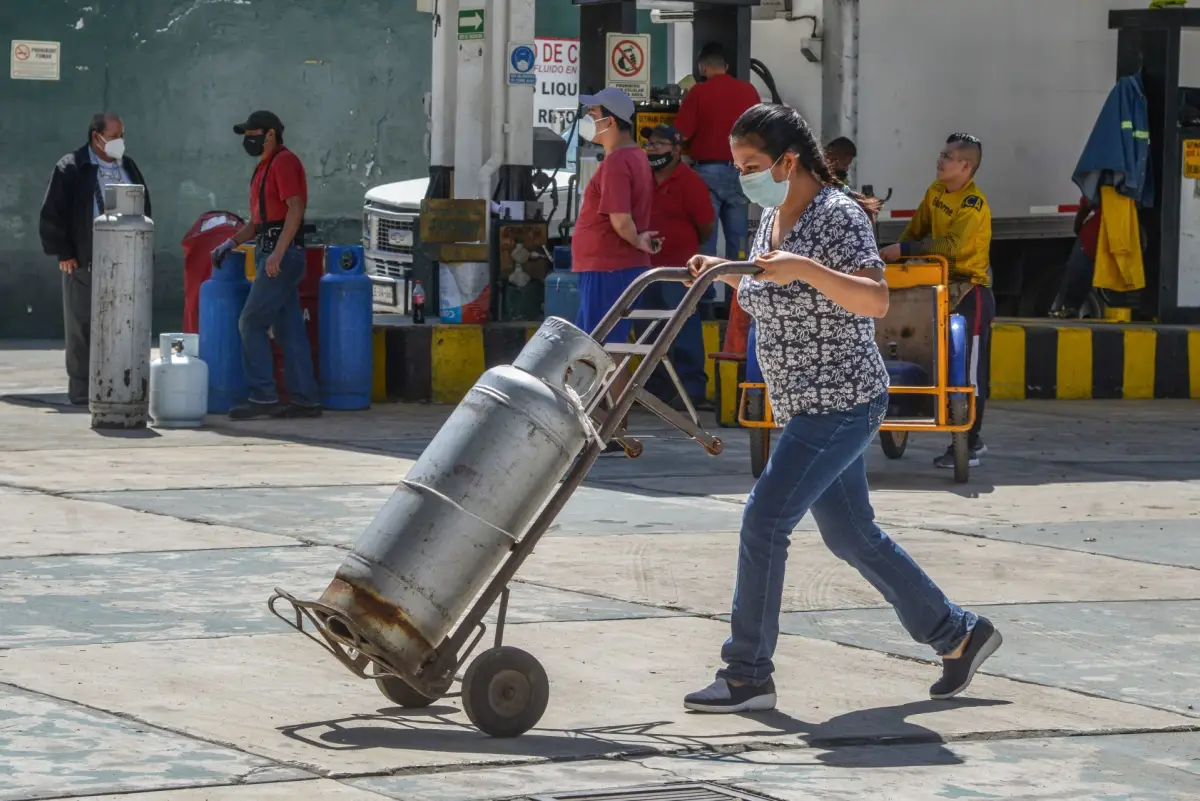 Una mujer lleva su tanque de gas LP, cuyo precio promedio subió un 25% anual 