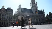 Los turistas caminan bajo sus paraguas para protegerse del sol mientras visitan la Gran Plaza, durante una ola de calor, en Bruselas el 24 de junio de 2026
