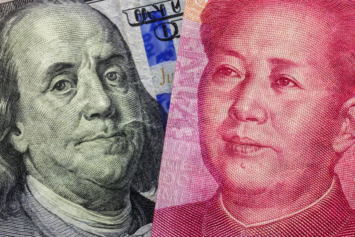 Close up of one hundred Dollar and 100 Yaun banknotes with focus on portraits of Benjamin Franklin and Mao Tse-tung/USA vs China trade war concept