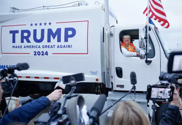 El expresidente Donald Trump arriba de una camión de basura (nuevo y limpio de color blanco) con su slogan de campaña "TRUMP Hagamos America Grande de nuevo.