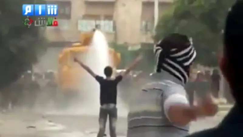 un manifestante se planta frente a un cañon de agua
