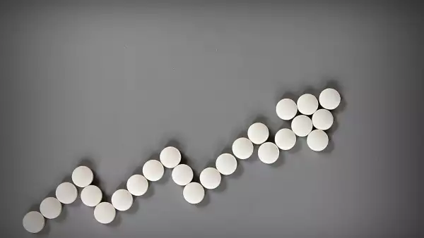 Top view or flat lay of rising graph cost of prescription drugs on gray background with copy space