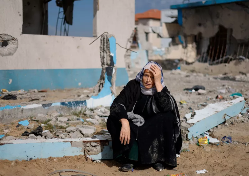 Una mujer descansa junto a un edificio dañado, mientras los palestinos llegan a Rafah después de haber sido evacuados del hospital Nasser en Khan Younis debido a la operación terrestre israelí, en medio del conflicto en curso entre Israel y Hamás, en el sur de la Franja de Gaza, el 15 de febrero de 2024. .