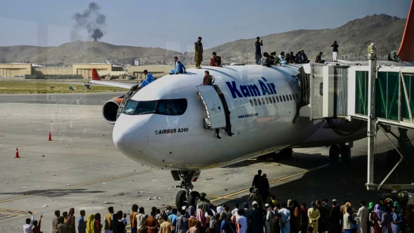 Personas afganas suben arriba de un avión que espera en el avión en el Aeropuerto de Kabul para huir del país tras la toma del poder de los talibanes.