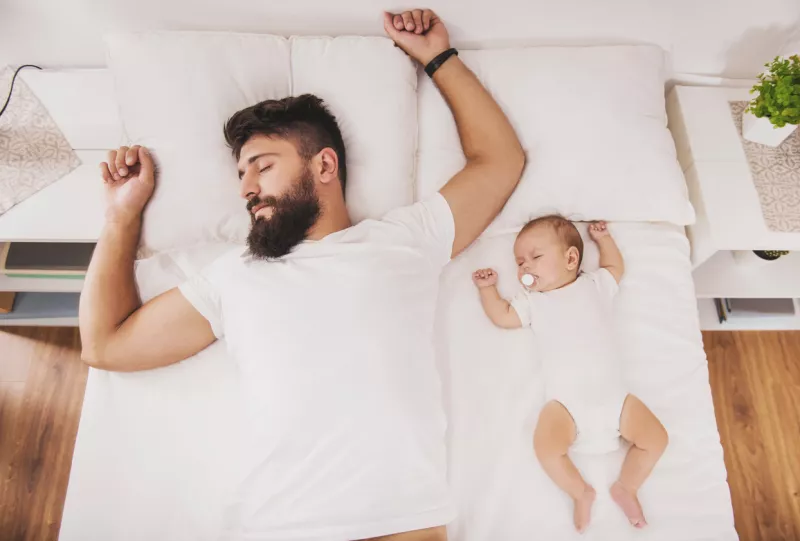 Top view. Bearded Father Sleeps with Baby in Bed.