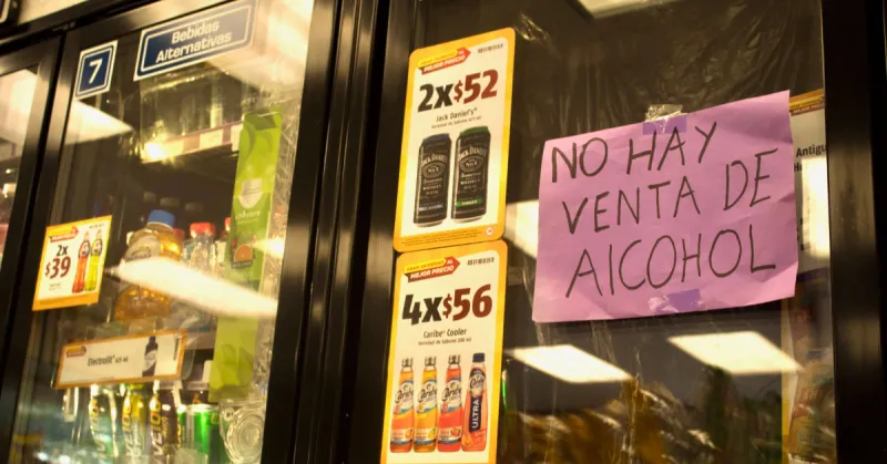 Dos refrigerados con un cartel rosa en donde dice que no hay venta de alcohol. Fotos con botellas de whiskey y caribe cooler.jpg