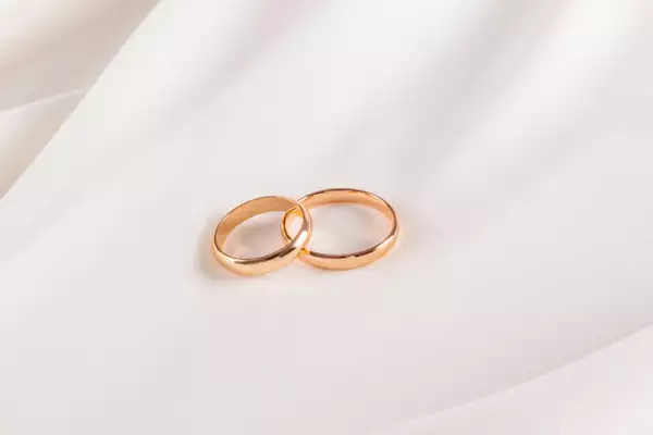 Two charming gold wedding rings on the soft surface of cream colored chiffon fabric. A copy of the space. wedding background. layout for design.