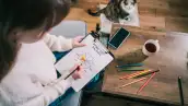 Woman drawing work-life balance wheel sitting on the sofa at home. 