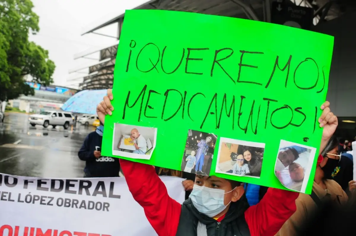 Un niño utiliza una cartulina para exigir medicamentos contra el cáncer.