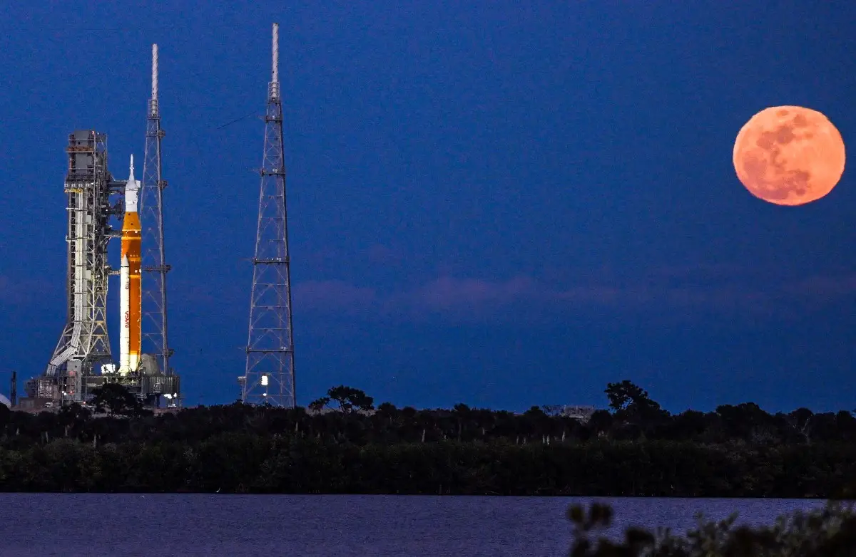 Una luna llena se levanta cuando el cohete del Sistema de Lanzamiento Espacial (SLS) y la nave espacial Orion, integrados para la misión Artemis II, se ven en la plataforma de lanzamiento 39B en el Centro Espacial Kennedy en Cabo Cañaveral, Florida, el 1 de febrero de 2026 antes de la primera misión tripulada a la Luna en más de 50 años.