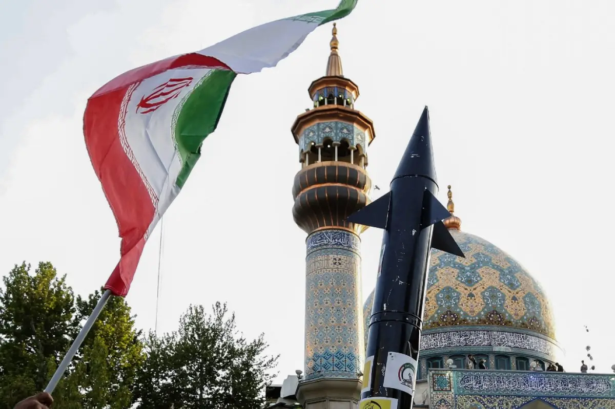 Los iraníes levantan una bandera y la maqueta de un misil durante una celebración tras el ataque de misiles y drones de Irán a Israel, el 15 de abril de 2024, en la plaza de Palestina en el centro de Teherán.