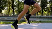 close-up legs male runner running race on road in park