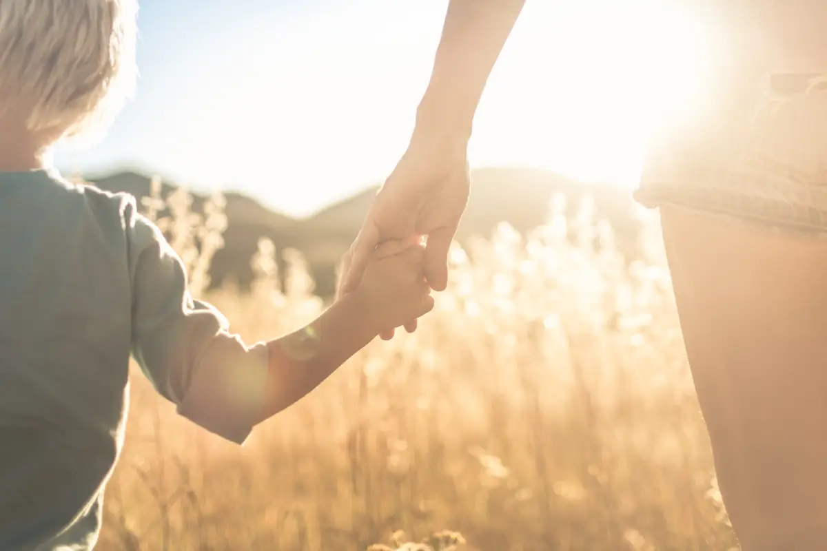 Niño de edad preescolar tomado de la mano de su mamá 