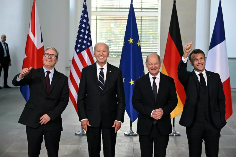 La imagen muestra sonrientes (de izquiera a derecha) al primer ministro británico Kier Stramer, el presidente estadounidense Joe Biden, al canciller alemán Olaf Scholz y al presidente de Francia, Emmanual Macron después de reunirse para discutir diversos asuntos. Detrás de ellos estan las banderas de Reino Unido, Estados Unidos, la Unión Europea, Alemania y Francia.