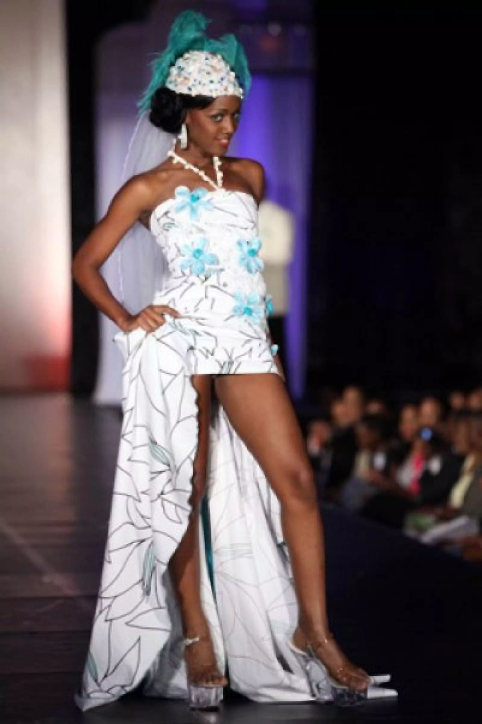 Kiara Sherman, de Bahamas, portó un vestido corto con una larga cola en color blanco y flores azules. Como complemento, un pequeño sobrero que le dio un aire de antaño.