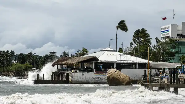 Unas olas de gran altura rompen contra el malecón mientras ondea una bandera roja de advertencia frente a la oficina de la Capitanía de Puerto en el puerto turístico de Acapulco, estado de Guerrero, México, el 28 de septiembre de 2026, alertando a las embarcaciones para que no zarpen ante la llegada de la tormenta tropical Rachel. (Foto de Francisco ROBLES / AFP)