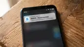 Celular en una mesa de madera, en la pantalla se ve una notificiación de un mensaje sms del banco.