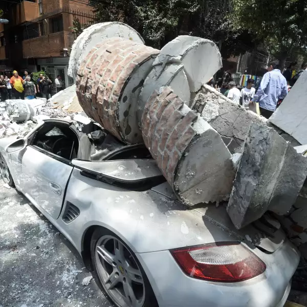 A car crushed by debris from a damaged building after a quake rattled 