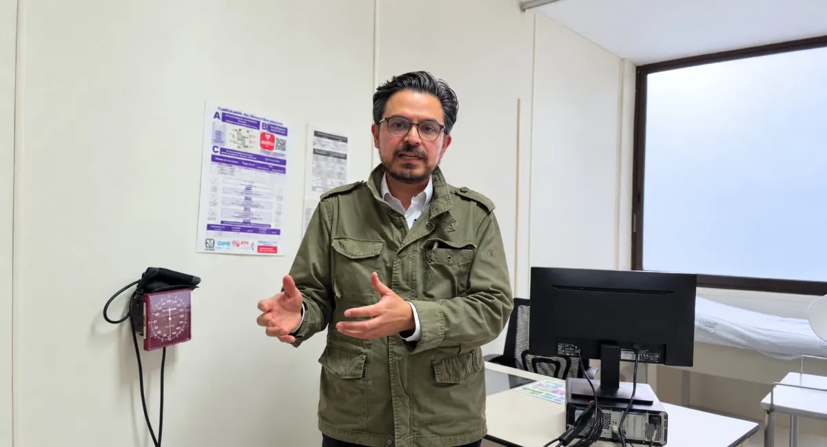 Zoé Robledo, director general del IMSS, habla frente a una cámara en un consultorio médico, con equipo de atención y una computadora al fondo.