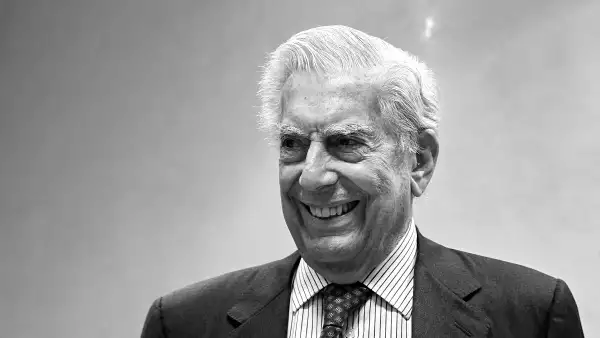 Foto en blanco y negro de Mario Vargas Llosa vestido de traje y corbata y sonriendo (Madrid, año 2021)