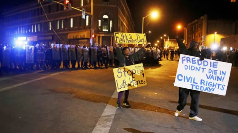 Un grupo de manifestantes frente a los policías del Departamento de Baltimore por la muerte de Freddie Gray, antes de un toque de queda