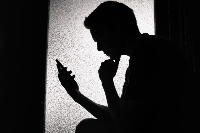 Young man reading on smartphone at home.