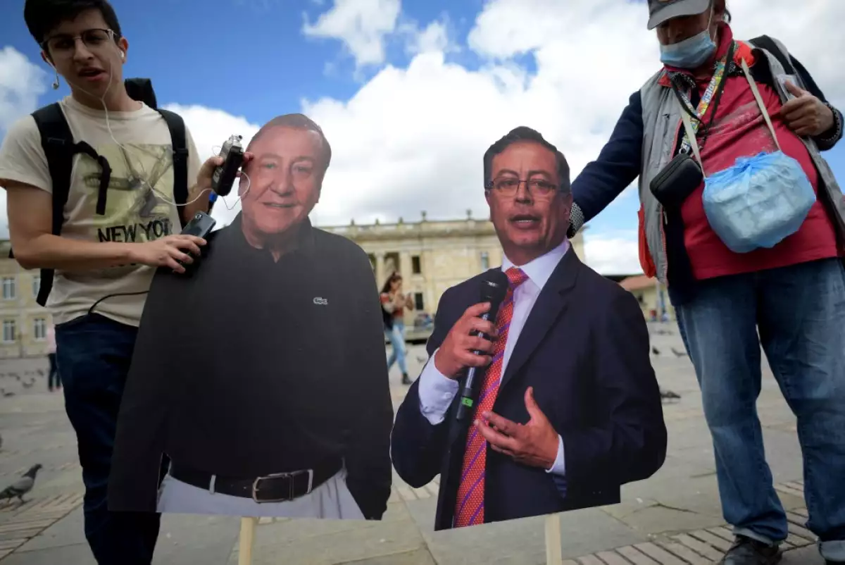 Un hombre sostiene dos figuras de cartón de los candidatos a la presidencia Rodolfo Hernández y Gustavo Petro en la Plaza Bolívar de Bogotá, Colombia. 