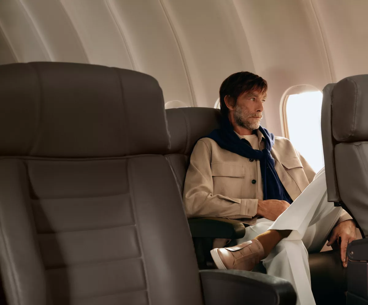 Foto de la marca Zegna de un hombre sentado junto a la ventanilla de un jet privado.