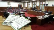 Acta de Nacimiento de México en primer plano sobre la mesa del estrado de la Suprema Corte de Justicia de la Nación, durante una sesión con ministros y público al fondo.