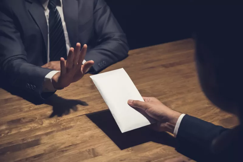 Businessman rejecting money in white envelope offered by his partner in the dark