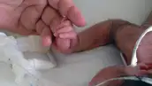 Recién nacido en un hospital toma el dedo de una persona. 