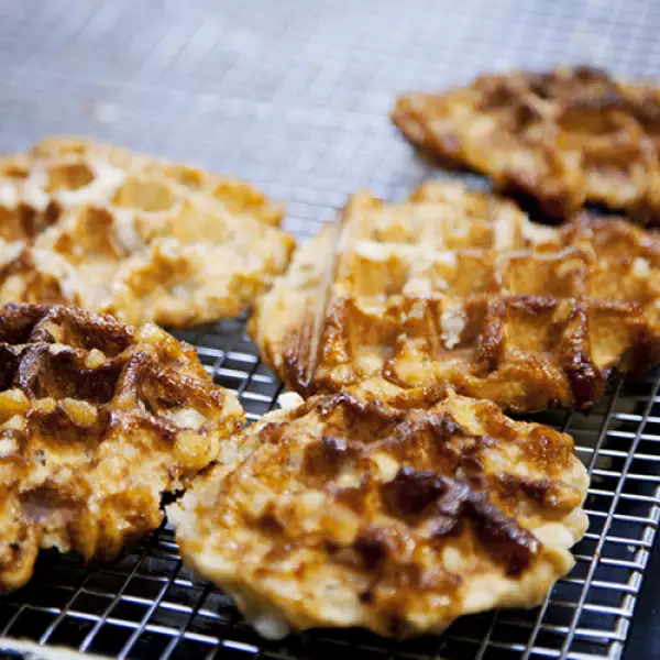 Los waffles de Hendricxs: “¿Los mismos de siempre?” pregunta la chica detrás de la caja a uno de los clientes frecuentes. Él elige un waffle, pequeño, redondo, crujiente, y para tomar, el belgium c...