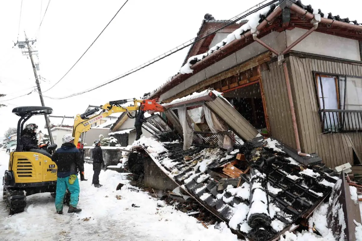 Esta foto tomada el 8 de enero de 2024 muestra a voluntarios demoliendo una casa parcialmente derrumbada porque el propietario estaba preocupado de que pudiera lesionar a los transeúntes en la ciudad de Suzu, prefectura de Ishikawa, una semana después de que un gran terremoto de magnitud 7,5 golpeara la región de Noto en la prefectura de Ishikawa el día de Año Nuevo.