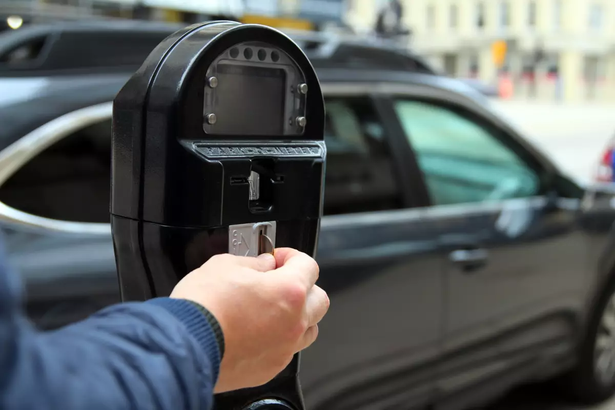 Man is paying  by coins for parking in the street  new with his car