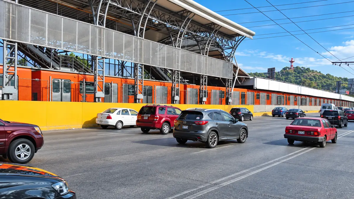 Exterior de la estación Oceanía de la Línea 5 del Metro de la Ciudad de México, con un tren naranja junto a la vialidad.
