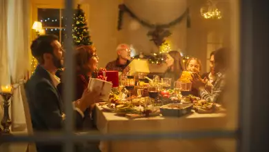 Foto de una familia reunida en una mesa durante la cena de Navidad e intercambiando regalos.