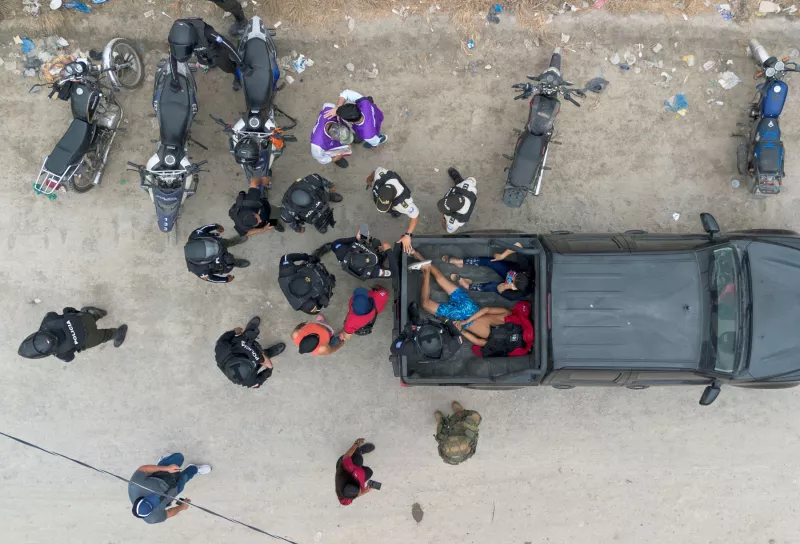 Una vista con un dron muestra a agentes de policía de pie alrededor de un hombre y una mujer que fueron detenidos después de ser encontrados escondidos en una casa abandonada con un chaleco antibalas, durante una operación gubernamental para devolver las casas, supuestamente robadas por bandas de narcotraficantes, a sus legítimos propietarios en Duran, Ecuador, el 19 de julio de 2024.